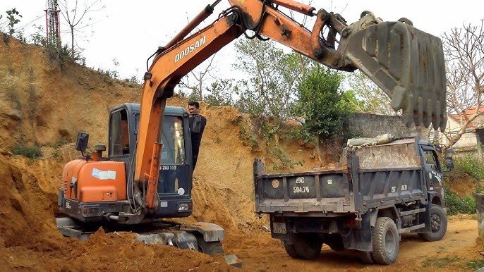 Xe máy múc đang bốc xúc vật liệu lên ô tô tải tại công trường